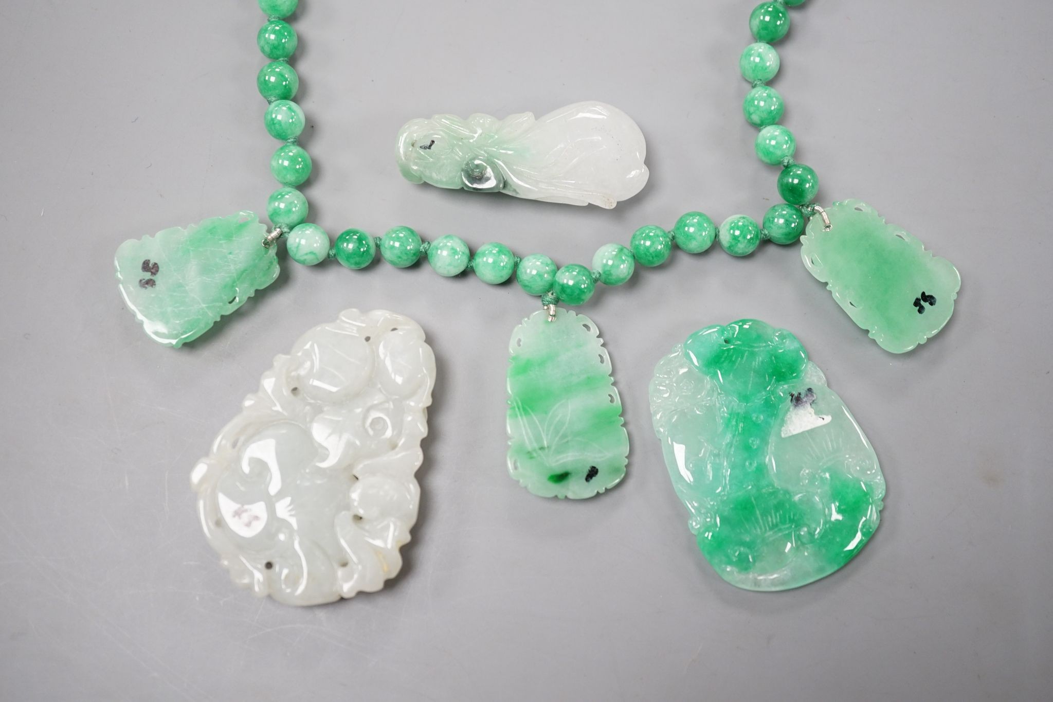 A jade bead necklace hung with three jade carvings, 49cm and three other jade carvings.